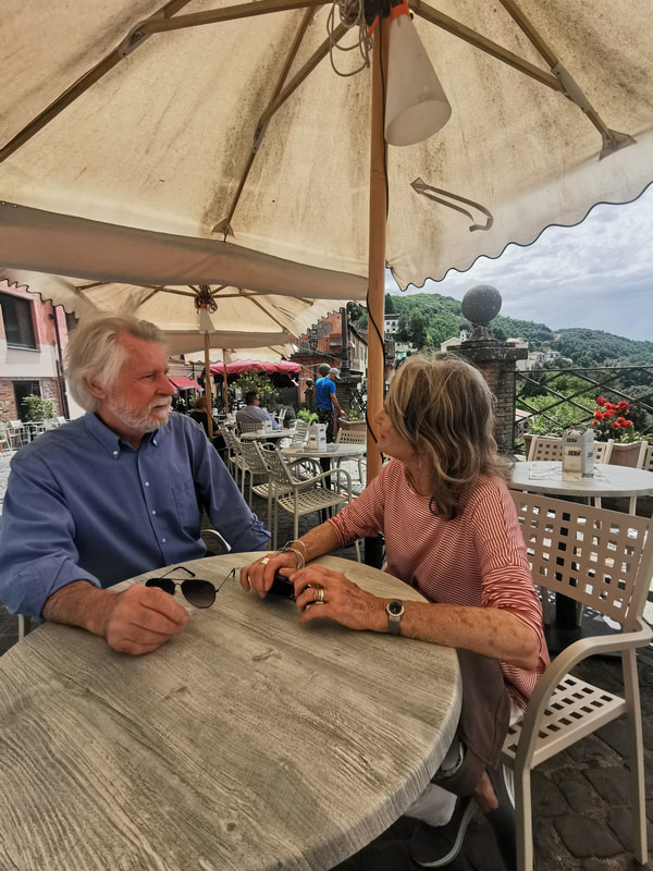A lovely couple sitting at a bar table, with a view of Nemi hills behind them